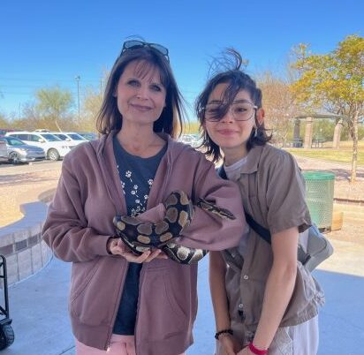 أستاذة العلوم البيطرية جيسيكا بيرغر وطالبة ISAZ ليندا هرنانديز تتفحصان ضيفًا خاصًا زلقًا في يوم المرح العائلي.